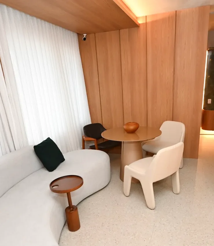 Sala de espera do INME com sofá curvo branco, mesa redonda e cortinas claras