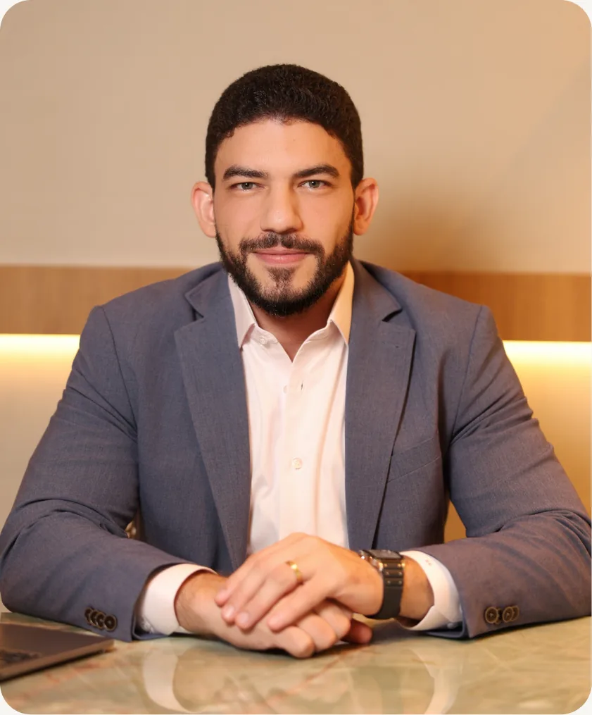 Dr. Ítalo César sentado à mesa do consultório, de terno, olhando para a câmera